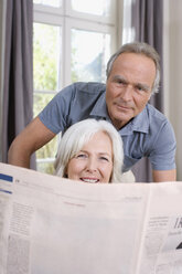 Senior Woman holding a newspaper, senior man behind, portrait - WESTF08202