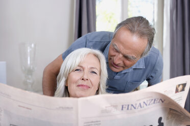 Senior Woman holding a newspaper, senior man behind, portrait - WESTF08201