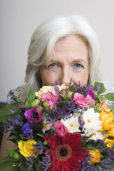 Senior woman holding bunch of flowers, portrait - WESTF08378