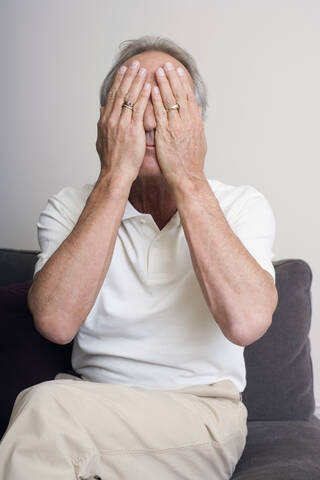 Älterer Mann, der sein Gesicht mit den Händen bedeckt, Porträt, lizenzfreies Stockfoto