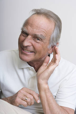 Älterer Mann mit Hand am Ohr, lächelnd, Porträt, lizenzfreies Stockfoto