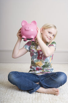 Girl (8-9) holding piggy bank, portrait - WESTF08348