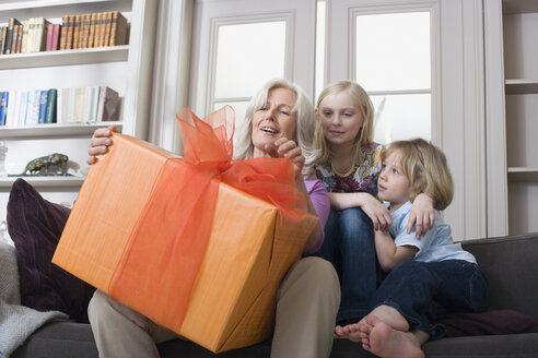 Grandmother and grandchildren (8-9) with gift - WESTF08342