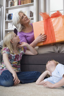 Grandmother and grandchildren (8-9) with gift - WESTF08341