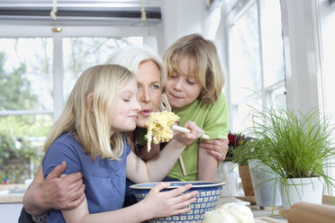 Großmutter und Enkelkinder (8-9) in der Küche, Zubereitung von Teig, Porträt - WESTF08304