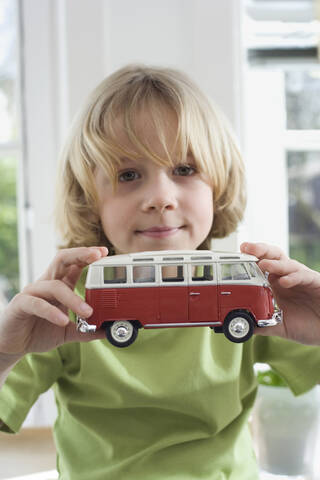 Junge (8-9) mit Spielzeugauto, Porträt, lizenzfreies Stockfoto