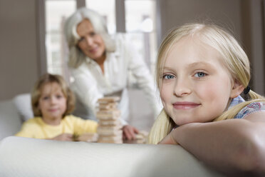 Grandmother and grandchildren (8-9) playing togehter, granddaughter in foreground, smiling, portrait - WESTF08276