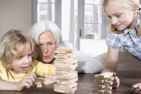 Großmutter und Enkelkinder (8-9) spielen zusammen, Porträt, lizenzfreies Stockfoto