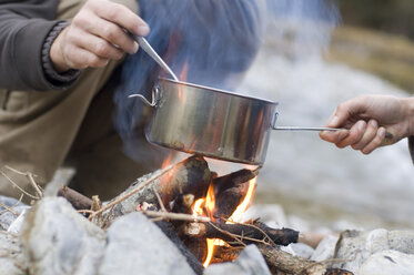 Österreich, Land Salzburg, Junges Paar beim Kochen am Lagerfeuer - HHF02446
