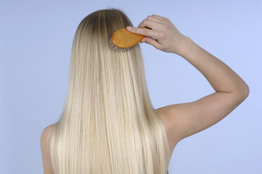 Junge Frau kämmt ihr Haar, Rückansicht - CRF01465