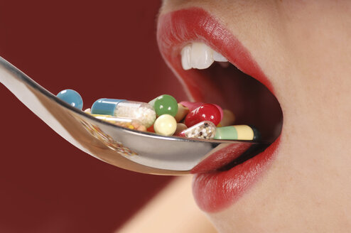 Woman taking a spoonful of pills - 00405LR-U