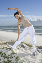 South Africa, Cape Town, Young woman stretching on beach - ABF00269