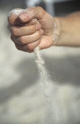 Italien, Sardinien, Mann lässt Sand durch die Finger gleiten, Nahaufnahme - LFF00129