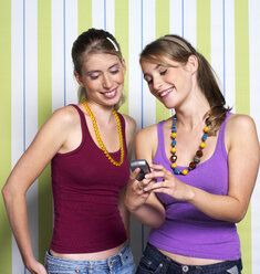 Two teenage girls (16-17) using mobile phone, portrait - JLF00293