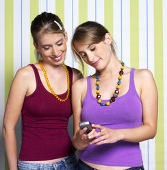 Zwei Mädchen im Teenageralter (16-17) mit Mobiltelefon, Porträt - JLF00292