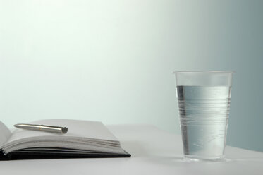 Ein Glas Wasser mit Stift und Notizbuch - ASF03696