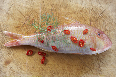 Raw Red Mullet, dill and chili pepper on chopping board, elevated view - KSWF00158