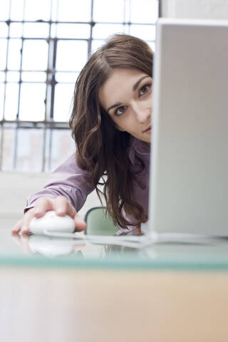 Junge Geschäftsfrau, die an einem Laptop arbeitet und herumalbert, lizenzfreies Stockfoto