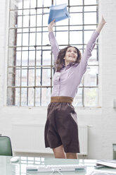 Young businesswoman standing in office, cheering - BMF00374