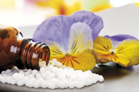 Arzneiflasche mit Tabletten vor Hornveilchen (Viola cornuta), Nahaufnahme, lizenzfreies Stockfoto