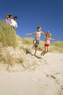 Deutschland, Ostsee, Familie in den Sanddünen, Kinder springen die Sanddünen hinunter - WESTF09355