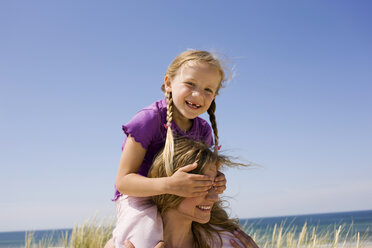 Germany, Baltic sea, Mother carrying daughter (6-7) on shoulders, portrait - WESTF09318