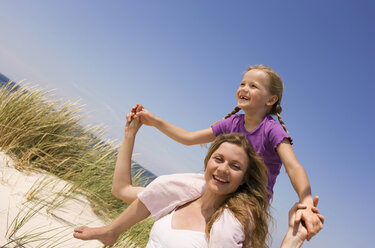 Germany, Baltic sea, Mother carrying daughter (6-7) on shoulders, portrait - WESTF09315