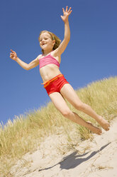 Germany, Baltic sea, Girl (6-7) jumping down sand dunes - WESTF09282