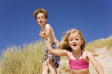 Germany, Baltic sea, Boy (8-9) and girl (6-7) jumping down beach dune - WESTF09280