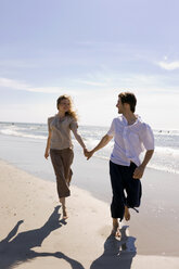 Germany, Baltic sea, Young couple walking across beach, holding hands - WESTF09261