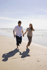 Germany, Baltic sea, Young couple walking along beach, holding hands - WESTF09260