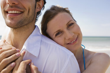 Deutschland, Ostsee, Junges Paar umarmt sich am Strand, lächelnd, Porträt - WESTF09252