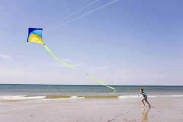 Deutschland, Ostsee, Junge (8-9) lässt Drachen am Strand steigen - WESTF09219