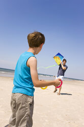 Deutschland, Ostsee, Vater mit Sohn (8-9) lässt Drachen am Strand steigen - WESTF09211