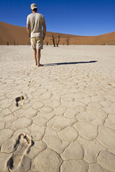 Africa, Namibia, Man walking in desert, rear view - FOF00963