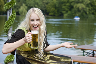 Deutschland, Bayern, München, Englischer Garten, Junge Frau hält Bierkrug - MAEF01123