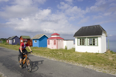 Denmark, Woman mountain biking alongside frame houses - DSF00187