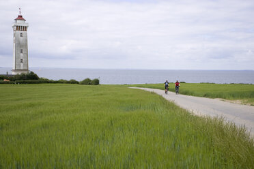 Dänemark, Fuenen, Mountainbike-Pärchen über Feldweg, Leuchtturm im Hintergrund - DSF00184
