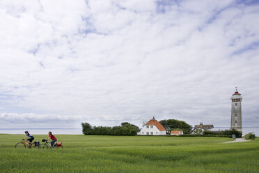 Dänemark, Fuenen, Mountainbike-Pärchen über Feldweg, Leuchtturm im Hintergrund - DSF00183