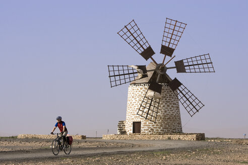 Spanien, Kanarische Inseln, Mann beim Mountainbiking, Windmühle im Hintergrund - DSF00170