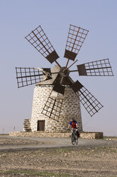 Spanien, Kanarische Inseln, Mann beim Mountainbiking, Windmühle im Hintergrund - DSF00169