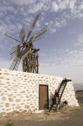 Spanien, Kanarische Inseln, Mann mit Mountainbike macht Pause an Windmühle - DSF00168