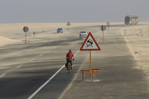 Spanien, Kanarische Inseln, Mann Mountainbike auf Autobahn, Verkehrsschild, glatte Straße - DSF00167