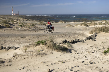 Spanien, Kanarische Inseln, Mann fährt mit dem Mountainbike über den Strand - DSF00166