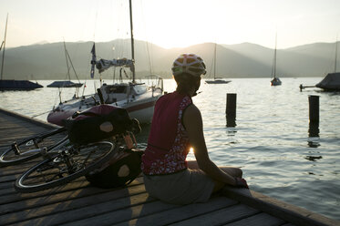 Germany, Bavaria, Tegernsee, Woman with mountainbike taking a break on landing stage - DSF00138