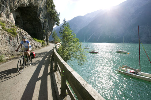 Austria, Tyrol, Achensee, Woman mountain biking lakeside - DSF00135