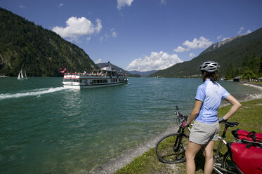 Österreich, Tirol, Achensee, Frau mit Mountainbike schaut am Seeufer aus - DSF00134