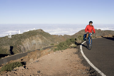 Spanien, Kanarische Inseln, La Palma, Frau beim Mountainbiken auf der Landstraße - DSF00125