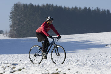 Deutschland, Bayern, Oberland, Mountainbiker fahren durch den Schnee - DSF00121