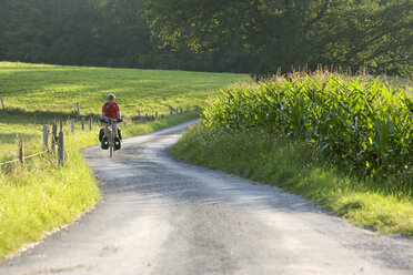 Deutschland, Bayern, Oberland, Mann fährt mit dem Mountainbike über einen Feldweg - DSF00112